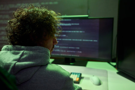 A young programmer codes intently in a dark setting, immersed in his work and creativity