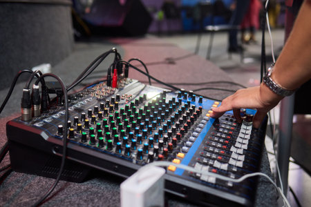 Closeup image of a hand mixing sounds on a control board, showcasing an audio technicians workの写真素材
