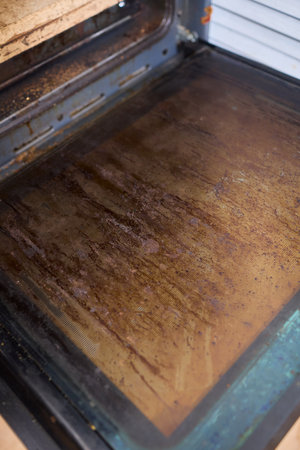 Interior of a dirty oven displaying baked on grease and unsightly stains throughout itの写真素材