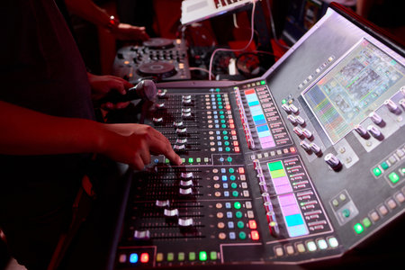 Closeup image of a hand mixing sounds on a control board, showcasing an audio technicians work