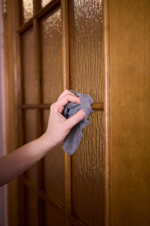 Carefully Hand Cleaning a Sparkling Glass Door with a Soft Sponge in the Kitchen Area