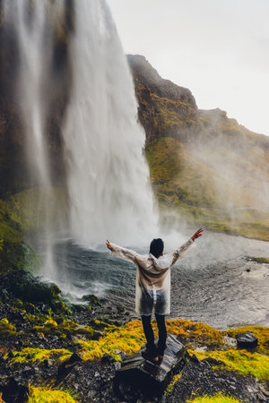 An adventurous traveler stands at a majestic waterfall in Iceland, absorbing its beauty