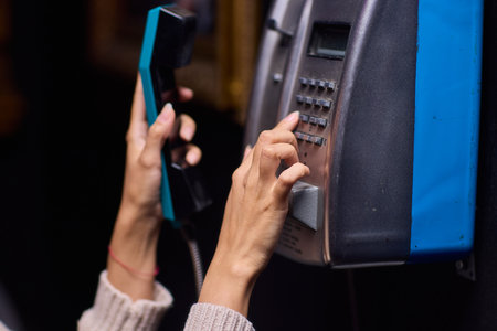 A Person Using a Payphone at Night in an Urban Setting, Highlighting Nostalgic Communication