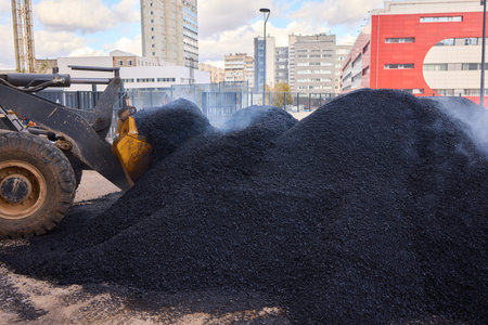 Heavy Machinery Loading Black Aggregate Material at the Construction Site for Developmentの写真素材