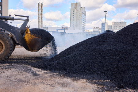Heavy Machinery Loading Black Aggregate Material at the Construction Site for Developmentの写真素材