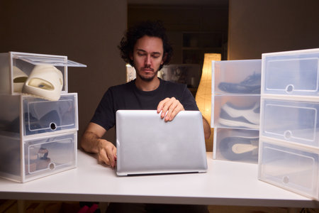 Individual systematically records shoe information on computer in workspace, Person carefully inputs sneaker details into spreadsheet within tidy home office environmentの写真素材