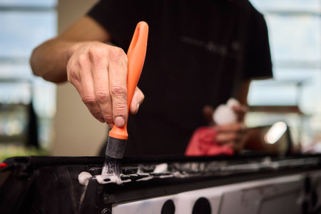 Car repair artistry, Closeup of technician carefully coating metallic car part, Focused craftsmanship as worker enhances vehicle surface with precise application of paintの写真素材