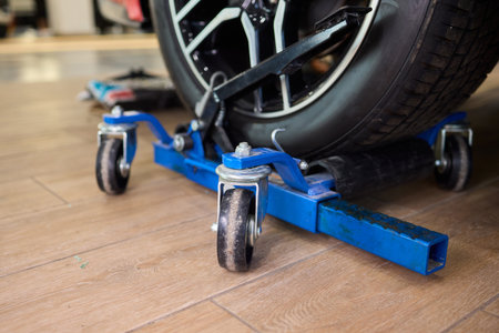Automotive technician repositioning car for proper alignment service, Garage setting with wheel on...