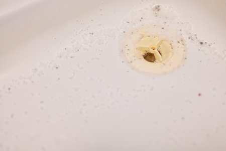 Closeup view of drainage system with grime and cleaning powder, Detailed image showing soiled bathtub drain and surrounding murky residue from maintenance effortsの写真素材