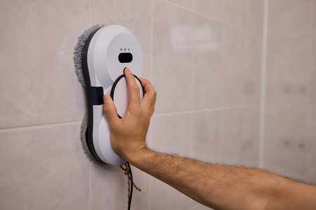 Smart robot performing quick hygienic maintenance in bathroom space, Modern robotic cleaner diligently scrubbing grout lines adjacent to toilet in bright tiled roomの写真素材