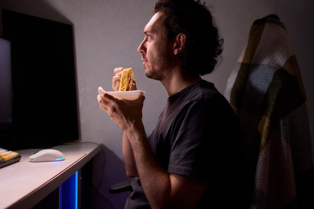 Live streaming snack, Content creator enjoys snack during livestream break, Casual moment captured during evening stream with ambient glow and home studio backgroundの写真素材