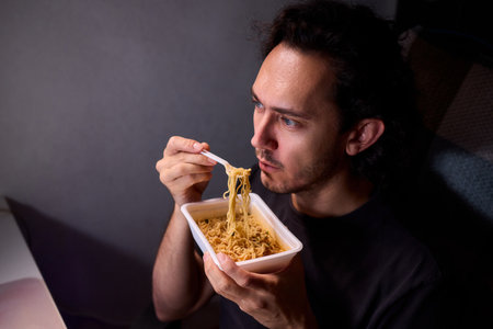 Content creator enjoys snack during livestream break, Casual moment captured during evening stream with ambient glow and home studio backgroundの写真素材