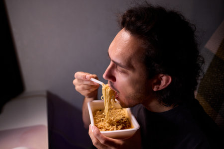 Live streaming snack, Content creator enjoys snack during livestream break, Casual moment captured during evening stream with ambient glow and home studio backgroundの写真素材