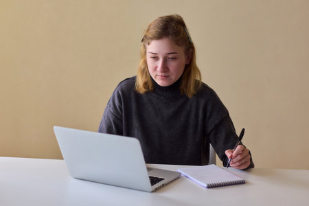 Determined individual with cerebral palsy immersed in educational activities indoors, Woman with cerebral palsy concentrates on studying at home with dedicationの写真素材