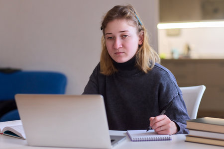 Determined individual with cerebral palsy immersed in educational activities indoors, Courageous woman with cerebral palsy concentrates on studying at home with dedicationの写真素材