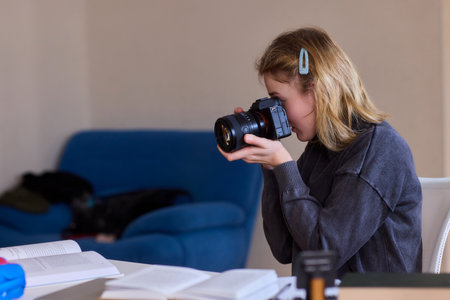 A young woman views her snapshot collection, Joyful young woman analyzes her pictures meticulously while seated in brightly illuminated kitchen environment with various decorationsの写真素材