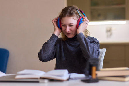 Young lady with cerebral palsy studying using technological aids, Enthusiastic woman with cerebral palsy learning with aid of modern assistive technology at bright workspaceの写真素材