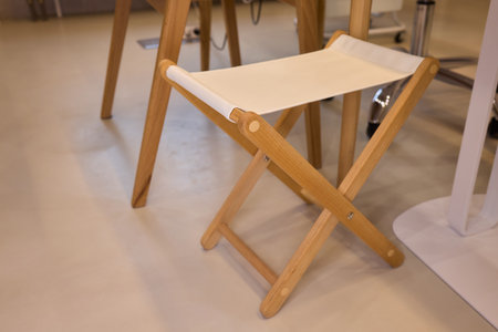 Collapsible wooden bench featuring fabric seat in modern , Versatile foldaway wooden stool with fabric surface situated in bright Scandinavian inspired settingの写真素材