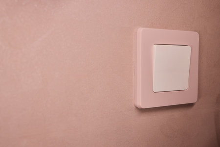 Pink textured wall, Minimalist interior featuring pastel wall and vintage modern contrast, Aesthetic of subtle shadows on soft pink wall with vintage modern switch designの写真素材