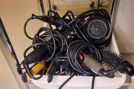 Chaotic styling station, Messy salon tools and cables, Disorganized hair dryer and equipment setup, Cluttered collection of salon devices and tangled wiring messの写真素材
