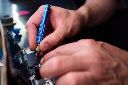 Technician repairing circuit, Closeup of skilled technician fixing smartphone circuitry, Focused technician meticulously reconnecting circuit pathways on cluttered workbenchの写真素材