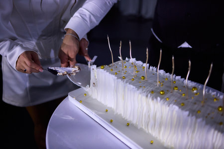 Couple shares wedding cake, Bride and groom enjoy their special cake moment together, Bride and groom cheerfully cut their elegant wedding cake amid joy and celebrationの写真素材