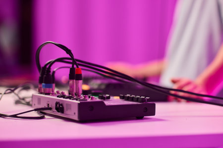 Closeup of tactile controls and vibrant patch cords in studio, Adjusting analog sequencing equipment with bright cables and warm ambient lighting in home studioの写真素材