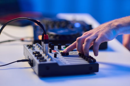 Closeup of tactile controls and vibrant patch cords in studio, Adjusting analog sequencing equipment with bright cables and warm ambient lighting in home studioの写真素材