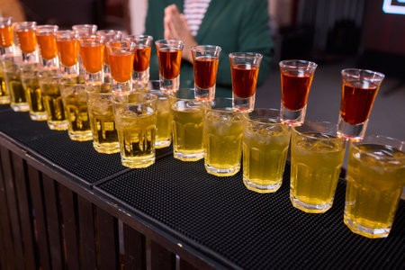 Celebratory drink scene, Orange liqueur shots at bar, Bartender pours drinks amidst lively party...