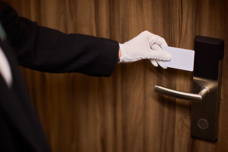 Guest room keycard insertion. Professional service in quiet luxurious hotel corridor. Formal suit...