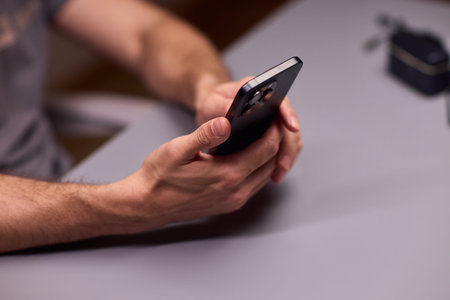 Individual operating sales application on smartphone over grey table. Focus on hands navigating...