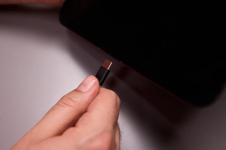 Closeup of hand with charger. Detailed view of hand plugging in smartphone charger cable. Intimate...