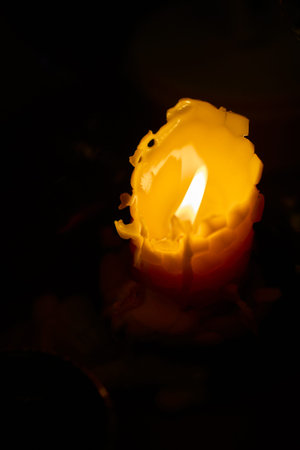 Serene scene with flickering candle and blurred background objects. Gentle lighting from candle creates inviting atmosphere with textured shadows and reflectionsの写真素材