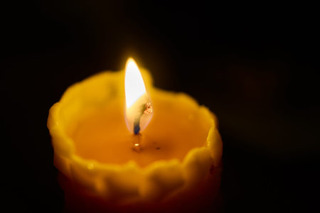 Serene scene with flickering candle and blurred background objects. Gentle lighting from candle...
