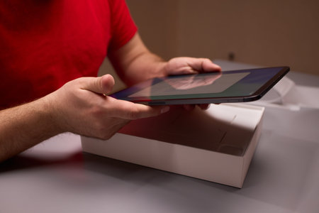 Testing new tablet. Conducting thorough review of new tablet and accessories. Systematically unboxing and evaluating tablet and stylus within neutral testing environmentの写真素材