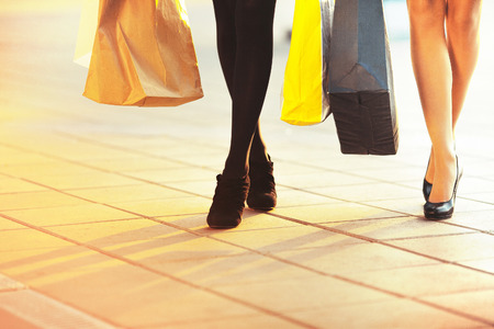 Legs of two glamorous girlfriends with paperbagsの写真素材