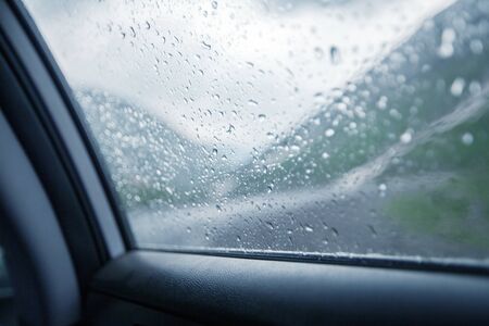 Rain drops on car glass. Inside view. Travel dramatic backgroundの写真素材