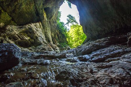 Mountain river creeck flowing in dark cave. Tropical nature view