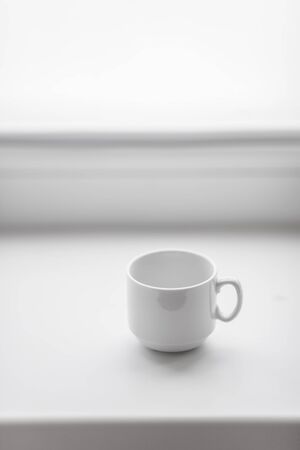 Empty white coffee cup on windowsill. Morning breakfast concept backgroundの写真素材