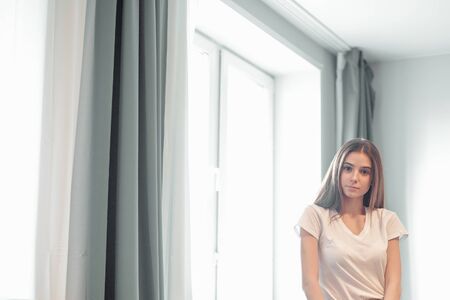 Beautiful young woman portrait behind window. Attractive caucasian model girl. Soft sun light....