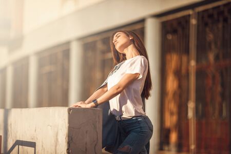 Fashion hipster cool girl relaxing on city street. Pensive female hipster model. Summer sunkight portraitの写真素材