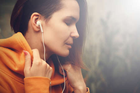 Beautiful Young Woman with Earphones Outdoors Enjoy Music. Hipster Girl Travelingの写真素材