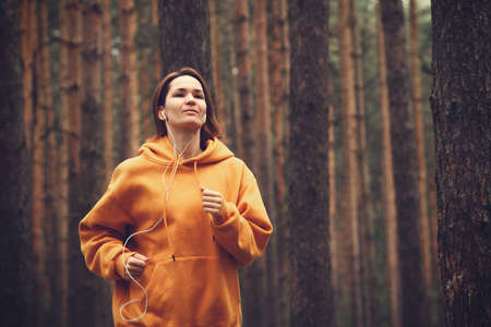 Hipster attractive girl in park using earphones. Pretty woman listening music