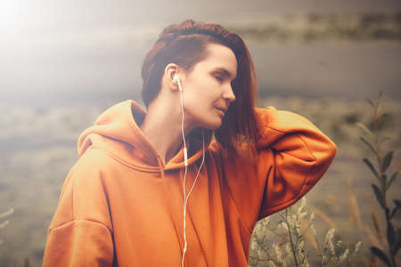 Beautiful Young Woman with Earphones Outdoors Enjoy Music. Hipster Girl Travelingの写真素材