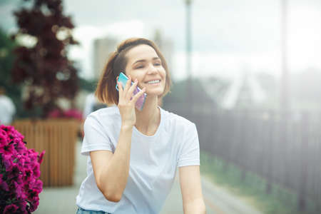 Attractive girl with phone in the street. City portrait of young beautiful woman model. Communication technologyの写真素材