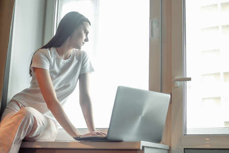 Girl working on computer laptop in light room. Woman chat in social network via net-book in modern interiorの写真素材