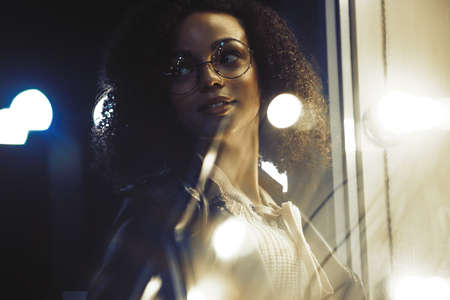 Portrait of young cute curly afro american girl. Night city lights. Neon illumination