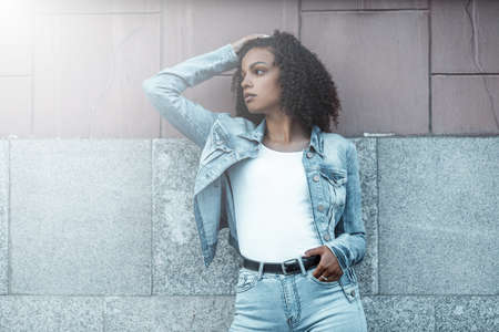 Attractive dark skin girl portrait. City hipster young woman walking on streetの写真素材