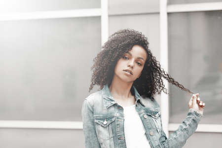 Denim style mulatto girl portrait. Hipster walking in summer cityの写真素材