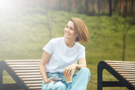 Young city girl with paper coffee cup. Attractive hipster woman with hot drinkの写真素材